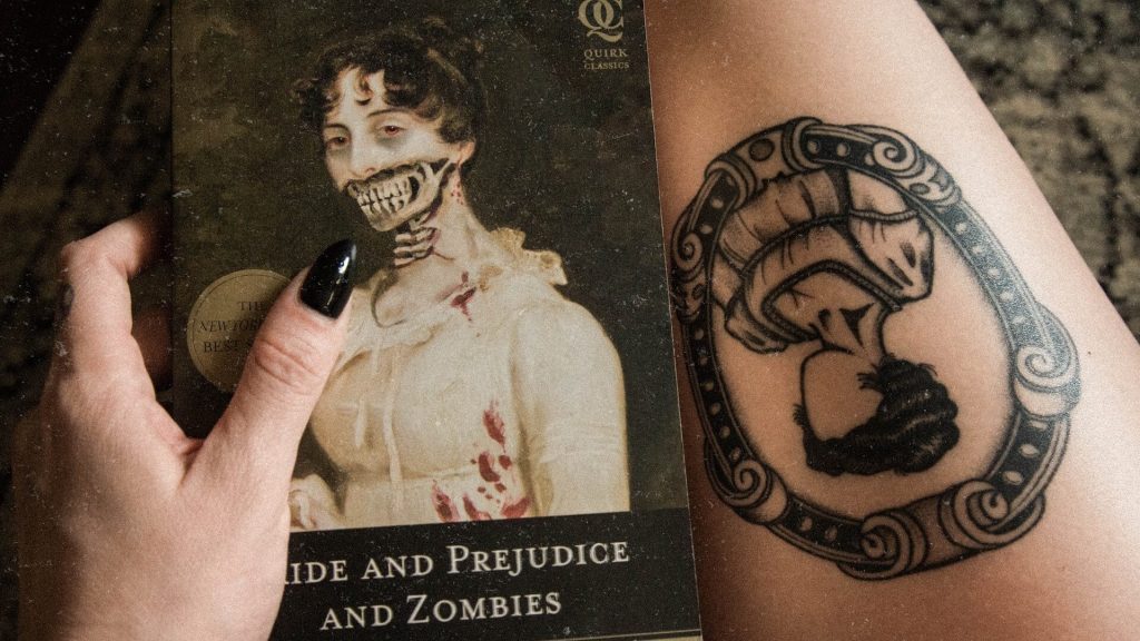 A girl holding a 'Pride and Prejudice and Zombies' book, with a tattoo of the same book cover.